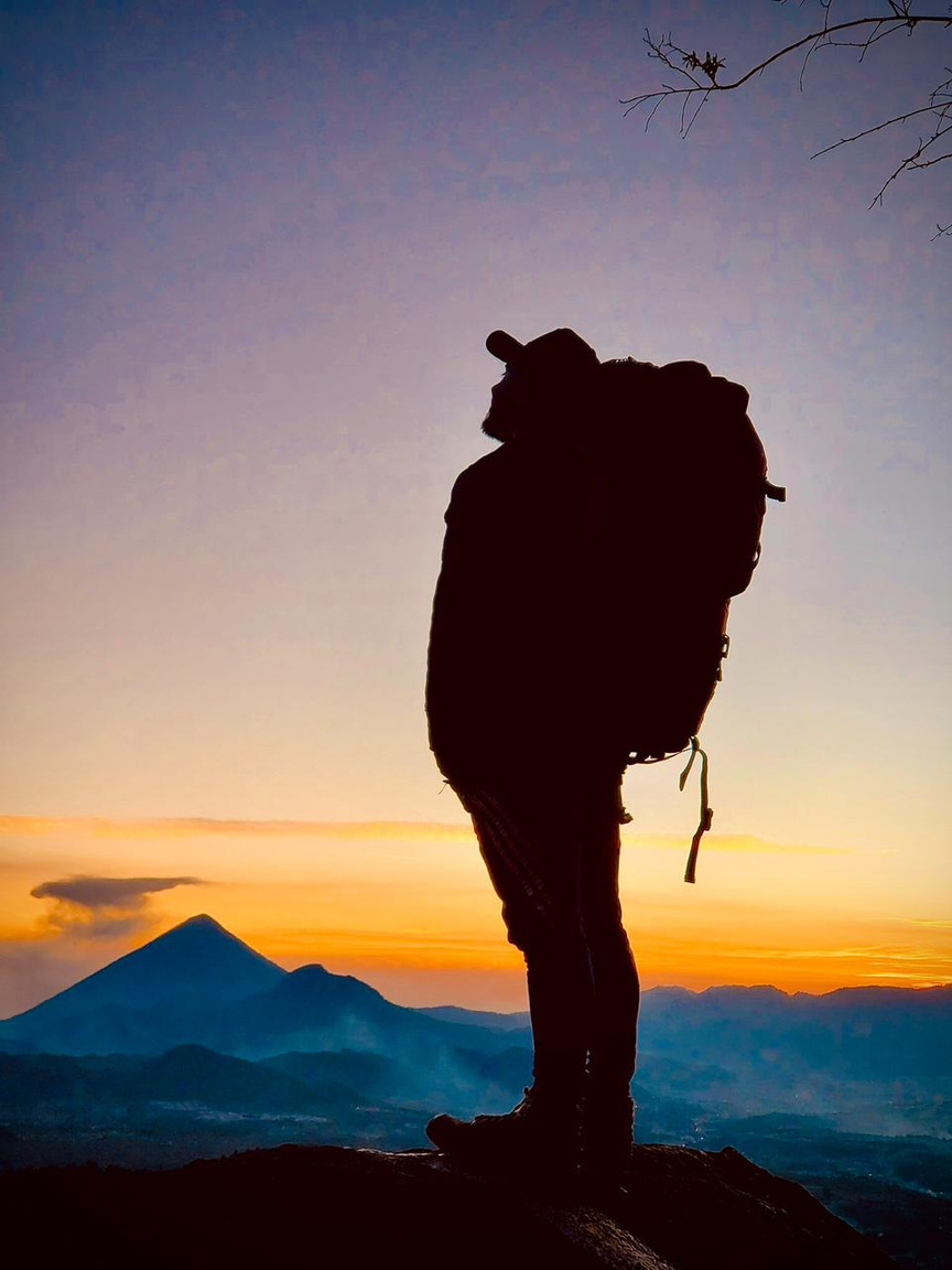 Senderista con mochila contemplando las montañas al amanecer